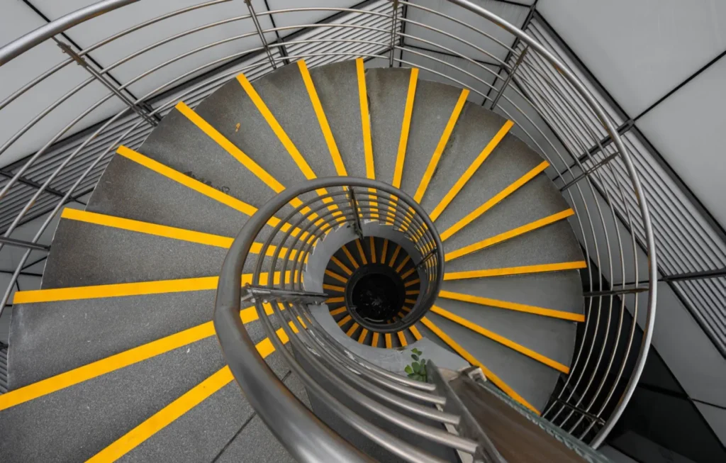 Steel spiral staircase with yellow anti-slip nosings on each tread, viewed from above