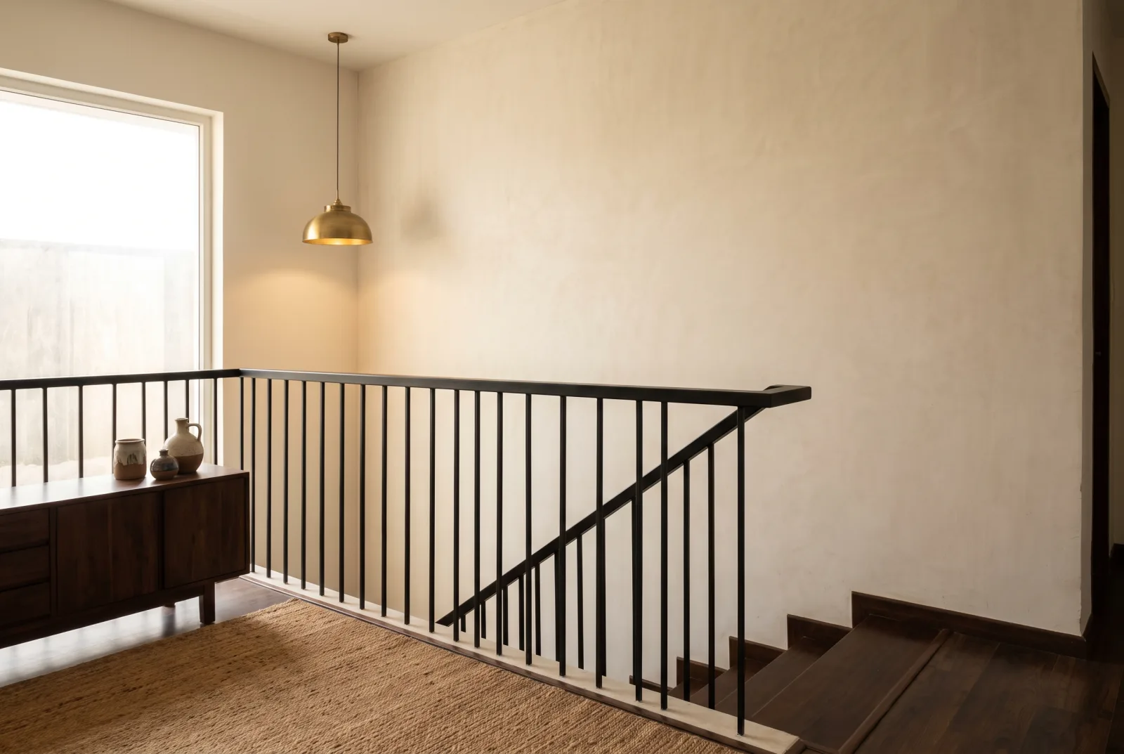 Slim matte black mild steel balusters and a flat steel top rail along an upper-floor landing with dark timber treads